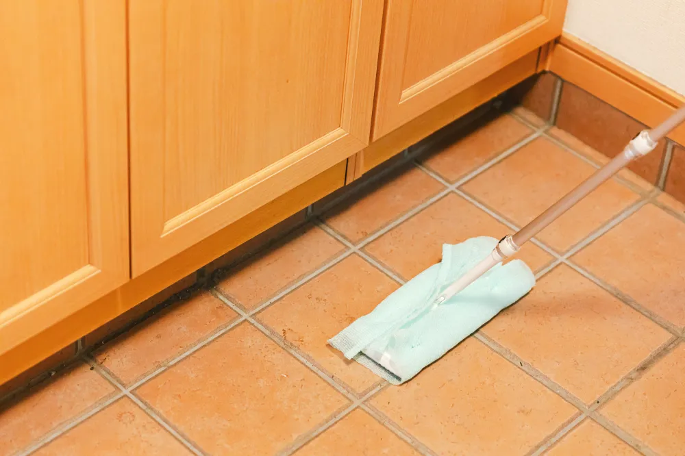 ④ フロアワイパーにタオルかナイロンのボディタオルを取り付ける。土間がビシャビシャになるくらい重曹水をかけ、床をゴシゴシとこすり洗いする